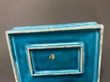 blue and white ceramic picture frame with a gold bead in the middle