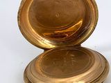 a gold pocket watch sitting on a white surface