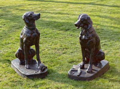 deux statues de chiens assis sur un skateboard dans l'herbe