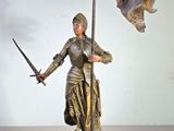 statue d'une femme tenant une épée et un drapeau, posée sur un socle en bois