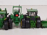 several toy tractors are lined up in a row on a white surface