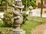 une statue d'ange posée sur un socle devant une maison