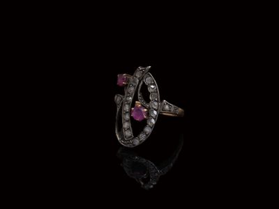 un gros plan d'une bague sertie d'un diamant et d'un rubis sur une surface noire