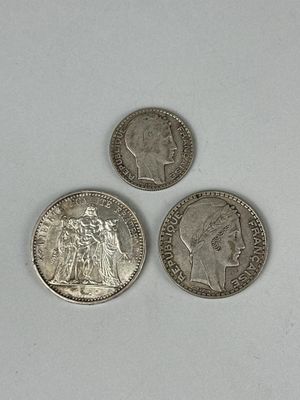 trois pièces d'argent posées l'une à côté de l'autre sur une surface blanche