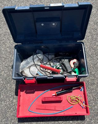 une boîte à outils contenant des outils, posée sur le sol