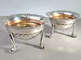 two silver bowls sitting next to each other on a table