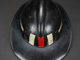 a black fireman ' s helmet with a red stripe on it