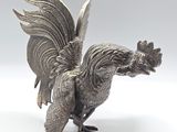 an antique silver plated rooster figurine on a white background