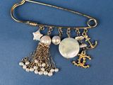 a close up of a brooch with pearls and charms on a blue background