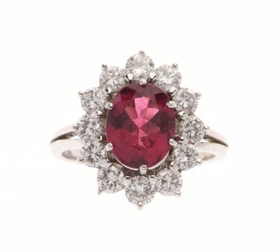 gros plan d'une bague avec une pierre rouge entourée de diamants blancs