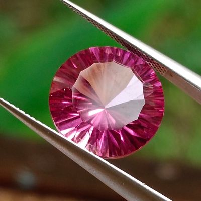 someone is holding a pair of pliers with a pink diamond in it