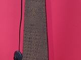 a tall wooden pole with a metal top against a pink wall