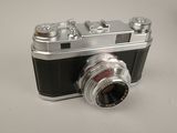 a silver and black camera sitting on a white surface
