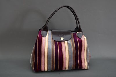 un gros plan d'un sac à main posé sur une table, sur fond gris