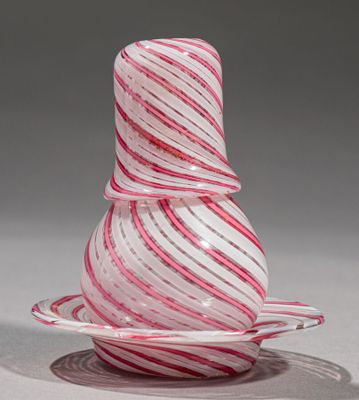 un vase en verre rayé de rouge et de blanc posé sur une soucoupe