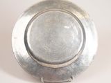a silver plate with a metal handle on a white surface