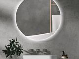 the bathroom vanity has a round mirror above it and a plant