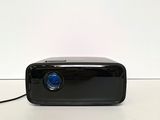 a small black projector sitting on a white surface