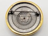 a close up of a silver and gold button on a white surface