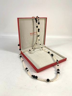 Ensemble composé d'un collier et d'un bracelet en perles noires et blanches, présenté dans un coffret rouge