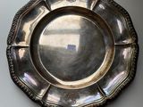 an antique silver plate on a white table next to a window
