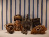 three masks that are sitting on a table in front of a striped wall