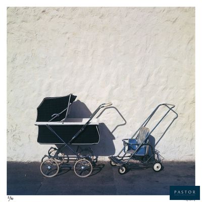 a baby carriage and a stroller next to a white wall
