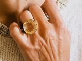 someone is wearing a gold ring with a yellow stone on it