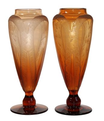 une paire de vases en verre orange posés sur des socles, sur fond blanc