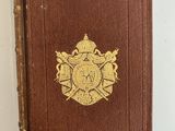 un vieux livre brun portant un emblème doré