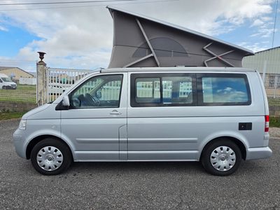a silver van parked in a parking lot with a tent on top of it