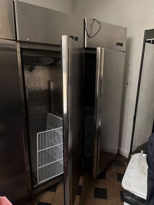 des réfrigérateurs et des congélateurs en acier inoxydable dans une cuisine dont le sol est recouvert d'un carrelage à damier noir et blanc