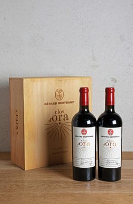 two bottles of red wine sitting next to a wooden box