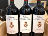 three bottles of red wine sit in a wooden box