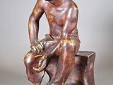 statue en bronze représentant un homme assis sur un rocher, coiffé d'un chapeau