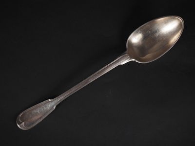 une vieille cuillère en argent avec un manche, sur fond noir