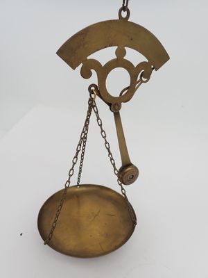 une balance ancienne en laiton à laquelle est suspendue une chaîne à l'arrière