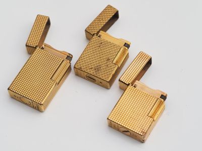 three gold lighters sitting on top of each other on a white surface