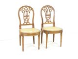 two wooden chairs with wicker seats on them against a white background