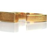 pair of gold plated cuff rings on white surface with reflection
