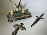 une petite statue représentant un aigle et une croix, à côté d'un couteau