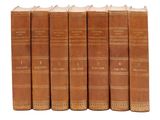 six vieux livres sont alignés sur une surface blanche