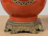 a red vase sitting on a stand on a table