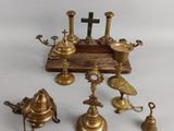 several antique brass bells and a cross on a wooden stand
