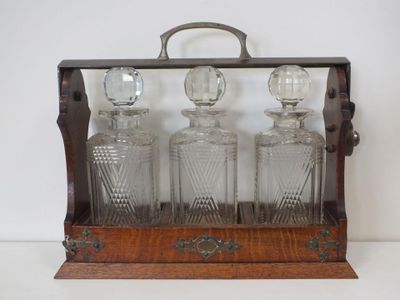 an old fashioned glass decanter with four bottles on a wooden stand