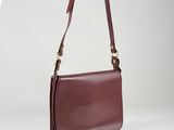 a brown leather shoulder bag with a long strap on a white background