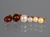three pairs of pearl and garnett earrings on a reflective surface
