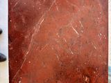 someone is holding a piece of red marble in their hand