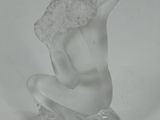 a glass figurine of a woman sitting on top of a coin