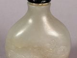 a white glass bottle with a black lid on a table